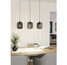 Drie metalen hanglampen hangen boven een eettafel en geven licht.