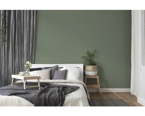 Slaapkamer met bed, nachtkastje en decoratie voor een groene wand