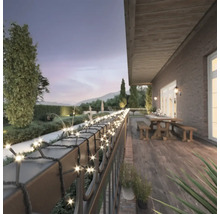 Terras met lichtsnoer op de balustrade, tafel en banken op de achtergrond.