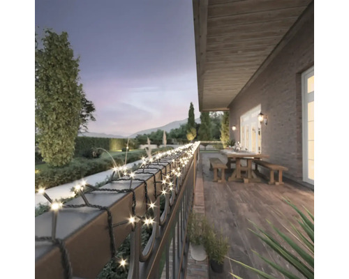 Terras met lichtsnoer op de balustrade, tafel en banken op de achtergrond.