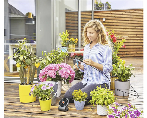 Vrouw knipt irrigatieslang voor planten op een terras
