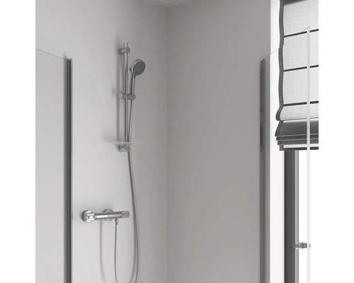 Douchearmatuur met handdouche en douchewand in badkamer.