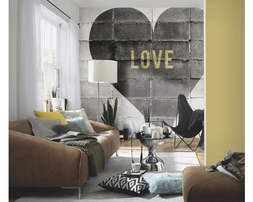 Woonkamer met bank, fauteuil en een behang met een betonnen hartmotief