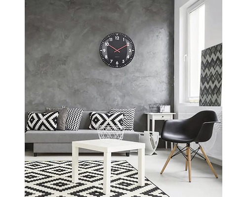 Woonkamer met bank, tafel, stoel, vloerkleed en wandklok