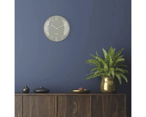 Woonkamer met wandklok, kamerplant en houten dressoir
