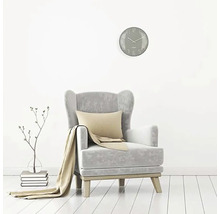 Woonkamer scène met fauteuil, kussen, deken, wandklok en decoratie