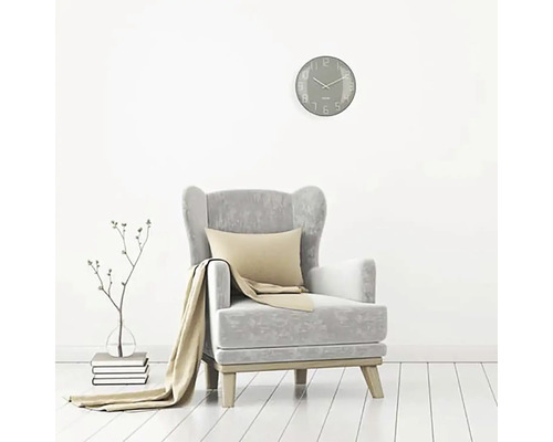 Woonkamer scène met fauteuil, kussen, deken, wandklok en decoratie