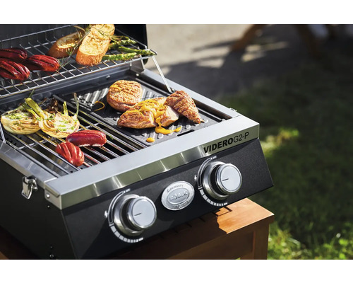 Gasbarbecue met eten op het grillrooster en warmhoudrek