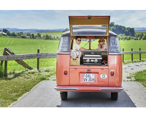 Achteraanzicht van een kampeerbus met open achterklep, waarin een grill, een mand en twee personen te zien zijn