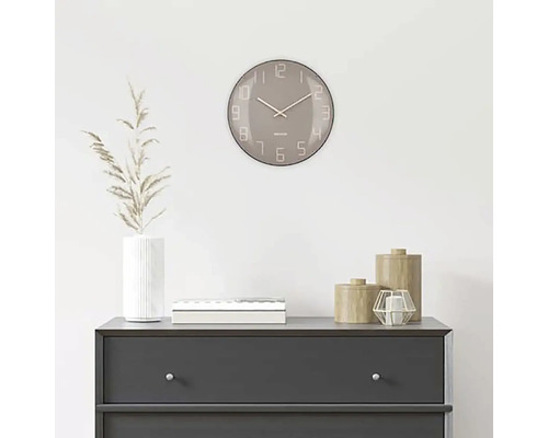 Decoratieve scène met een ronde wandklok boven een commode.