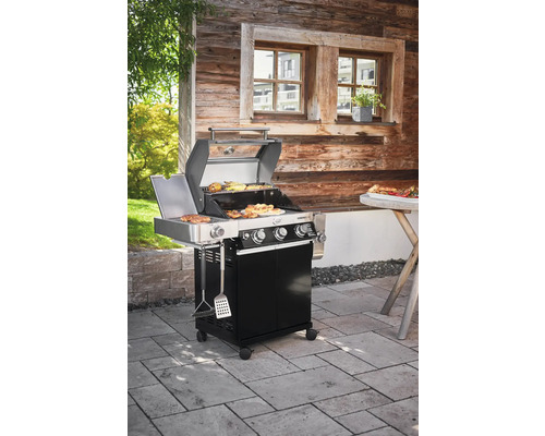 Gasbarbecue met eten op het grillrooster voor een houten hut