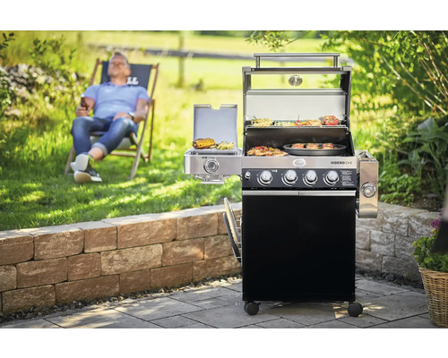 Gasbarbecue met gegrild voedsel in de tuin met ontspannen man op de achtergrond
