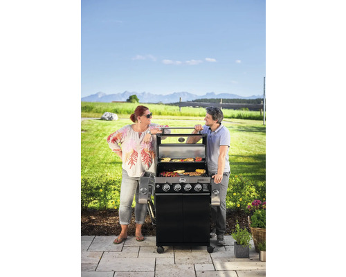 Gasbarbecue buiten met twee mensen die eten aan het grillen zijn