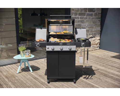 Buitenscène met een gasbarbecue, gegrild eten en een bijzettafel op een houten terras.