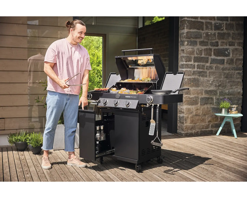 Man met grilltang bij een zwarte gasbarbecue buiten