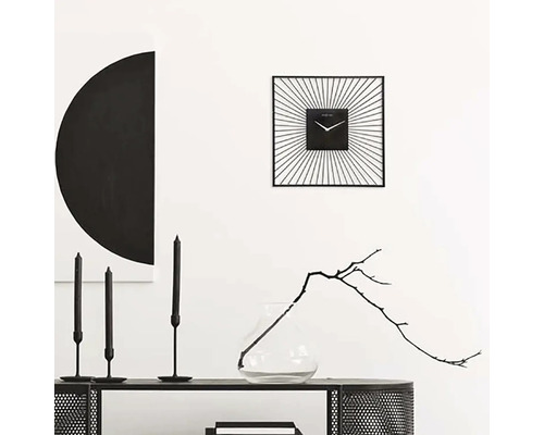 Decoratief interieur met een vierkante wandklok, kaarsen en een vaas met tak