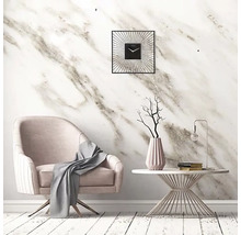 Woonkamer met fauteuil, tafel en wandklok voor een marmeren wand