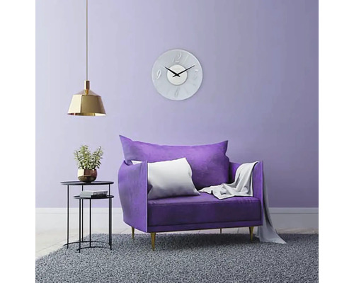 Woonkamer met fauteuil, wandklok, staande lamp en vloerkleed