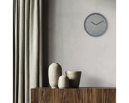 Scene met een grijze wandklok, drie vazen op een houten kast en een gordijn