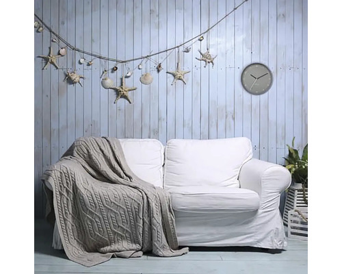 Woonkamer met witte bank, gebreide deken, wandklok en decoratie met schelpen en zeesterren