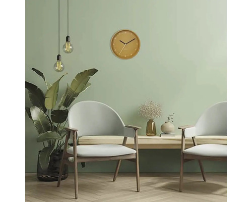 Lichte woonkamer met twee fauteuils, hanglampen en een ronde wandklok.