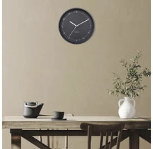 Wandklok boven een houten tafel met theepot en vaas