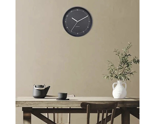 Wandklok boven een houten tafel met theepot en vaas