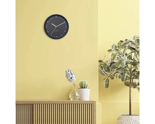 Woonkamer met wandklok, dressoir, potplanten en decoratie