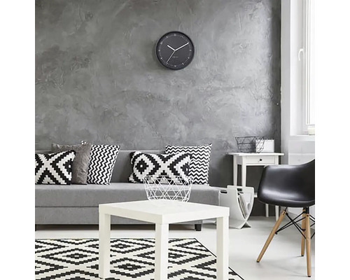 Woonkamer met bank, kussens, tafel, vloerkleed, stoel en wandklok