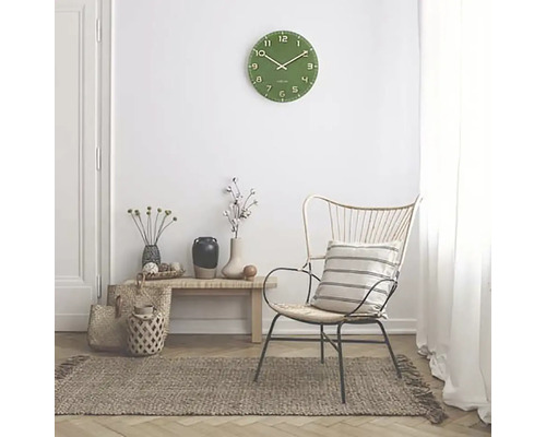 Woonkamer scène met groene wandklok, stoel en vloerkleed