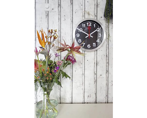 Wandklok met bloemenvaas op een tafel