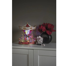 Decoratieve carrousel met verlichting, naast een glas marshmallows en een vaas met bloemen op een kast