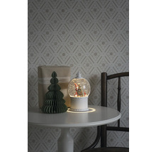 Decoratief arrangement met sneeuwbol, cadeau en papieren boom op een tafel