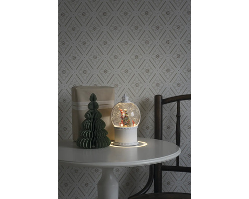 Decoratief arrangement met sneeuwbol, cadeau en papieren boom op een tafel