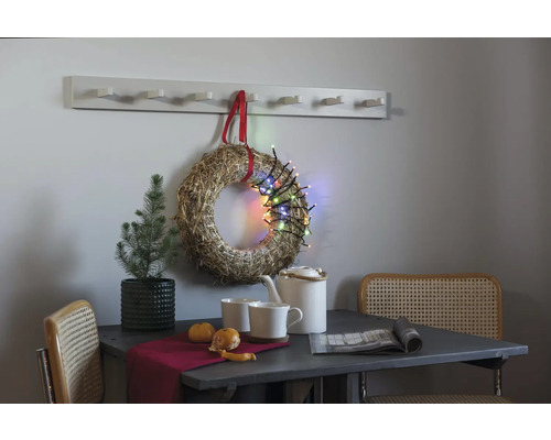 Decoratief stilleven met tafel, stoelen, krans, lichtsnoer en kapstok