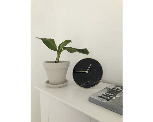 Tafeldecoratie met kamerplant in pot, ronde klok en boek