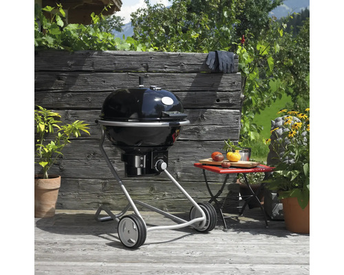 Kogelbarbecue op een houten terras, barbecuehandschoenen en bijzettafel