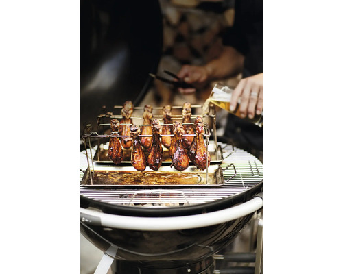 Kippenpoten op een barbecue met rooster en houder, plus een glas bier