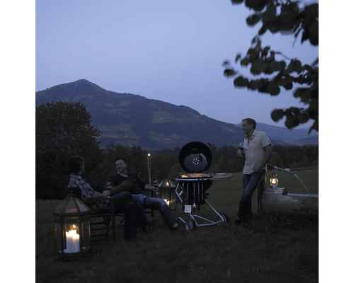 Scene met bol barbecue, mensen, tuinmeubelen en berglandschap op de achtergrond
