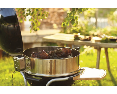 Bolgrill met draaispit en gegrild voedsel in de tuin