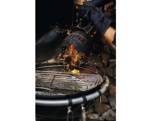 Houtskool wordt met een brikettenstarter in een barbecue gevuld.
