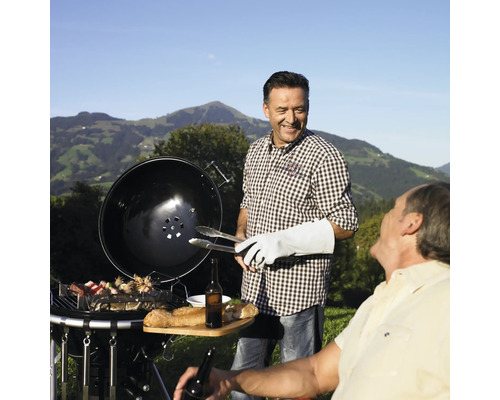 Twee mannen grillen buiten met een houtskoolgrill voor een berglandschap.