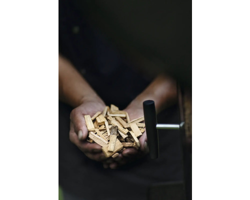 Een persoon houdt een handvol rooksnippers vast.