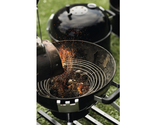 Houtskoolbarbecue met houtskool en brikettenstarter tijdens het aansteken