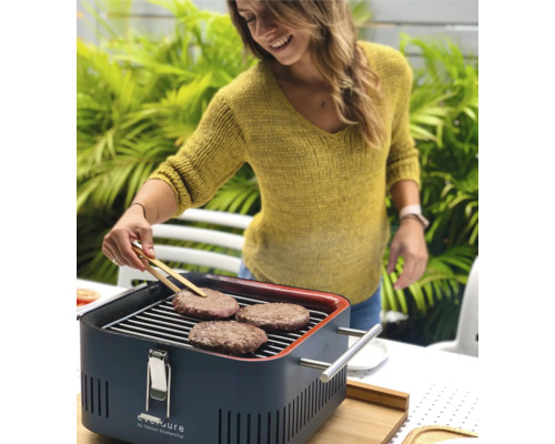 Vrouw grilt hamburgers op een houtskoolgrill buiten.