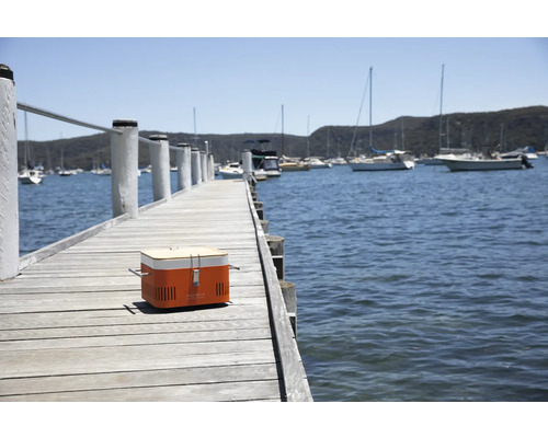 Draagbare houtskoolgrill op een houten steiger met uitzicht op het water
