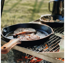 Steaks worden in een gietijzeren pan op een grill bereid.