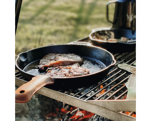 Steaks worden in een gietijzeren pan op een grill bereid.