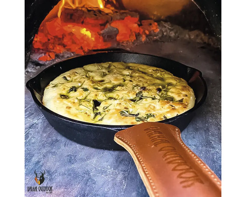 Brood in een gietijzeren pan in de oven met vuur.