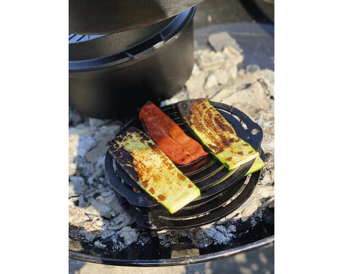 Gegrilde groenten op een rooster met een Dutch oven op de achtergrond.